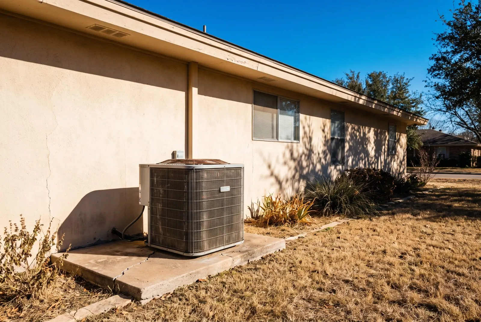 AC condenser beside a stucco home in hard summer sun