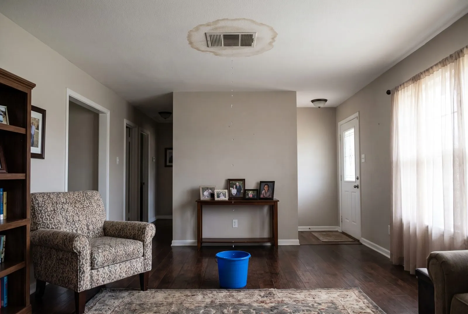 Water stain around a ceiling vent dripping into a bucket