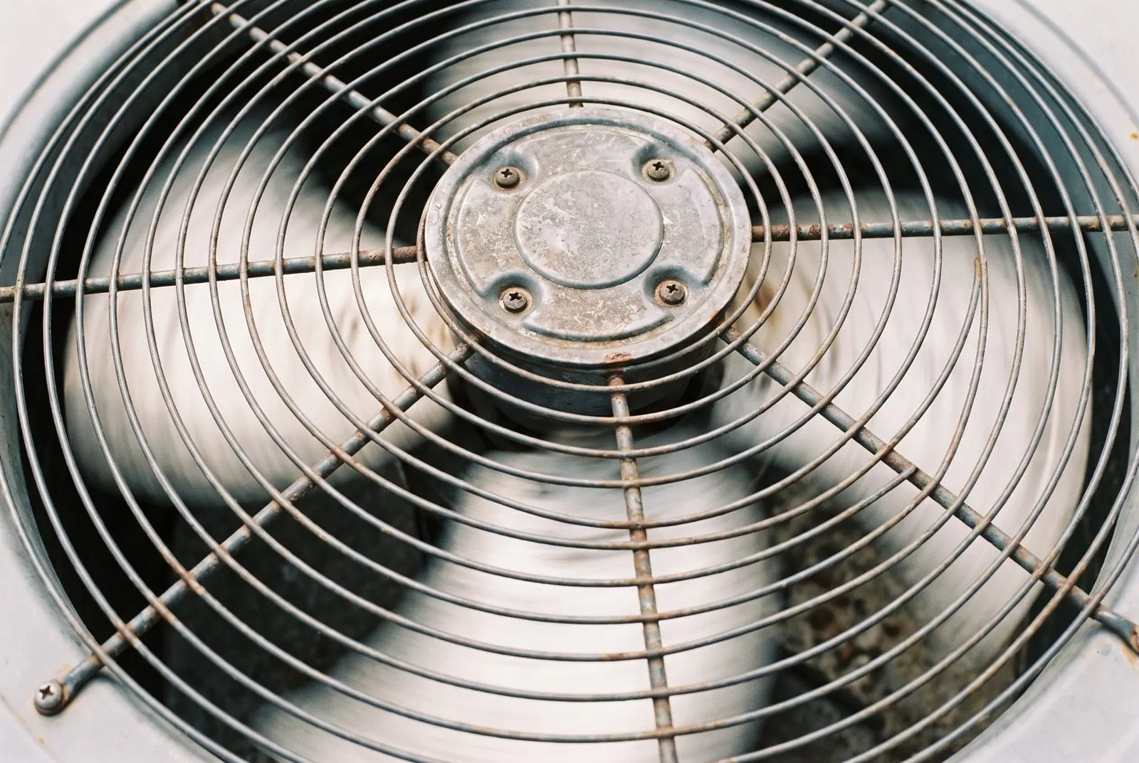 Close-up of a condenser fan spinning under its grille
