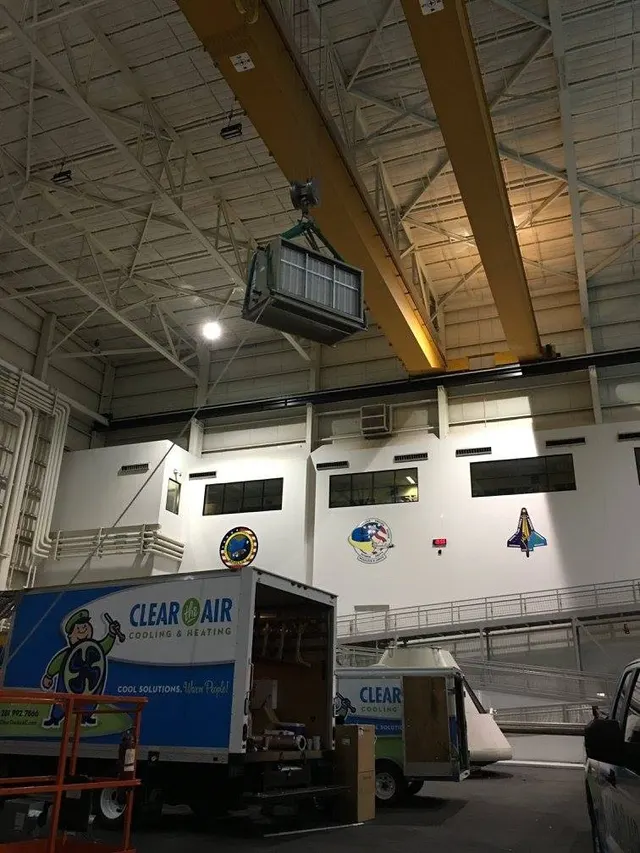 New air handler lifted by overhead crane during Clear the Air's install at NASA's Neutral Buoyancy Laboratory